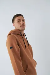 Buzo de algodón color marrón con capucha, bolsillo tipo canguro, mangas largas y logo estampado en el pecho.