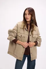 Campera de denim color marrón con diseño vintage, corte relajado y cuello de pana al tono. Presenta cierre frontal con botones metálicos, bolsillos con solapa en el pecho y bolsillos laterales.