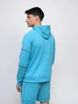 Campera deportiva Umbro de piqué, color celeste, con capucha, cierre frontal completo y detalles de piping en las mangas.