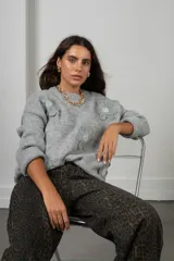 Buzo de punto gris con diseño oversize, cuello redondo y aplicaciones de flores de tela con centro de pedrería.