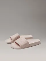 Ojotas de diseño anatómico con tira ancha superior estampada con el monograma de la marca. Presentan plantilla contorneada para mayor confort y suela de material sintético.