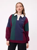 Sweater estilo rugby de Rusty, con diseño color block en tonos bordó, azul marino y verde. Presenta cuello polo en color crema con cierre frontal de botones, mangas largas con puños elásticos y logo de la marca bordado en el pecho.
