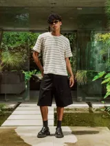 Remera de tejido de punto abierto, color crudo y beige, con diseño de rayas horizontales finas. Presenta cuello redondo y mangas cortas.