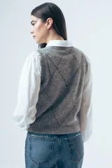 Chaleco de punto gris con diseño de rombos bordados en negro y cuello redondo. Presenta un corte clásico y tejido de textura suave.