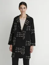 Tapado negro con estampado de texto en color blanco, cuello solapa y cierre frontal con un botón.