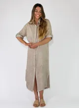 Vestido camisero midi de lino color beige, con cuello camisero, botonadura frontal completa, mangas cortas con presilla y tajos laterales en el ruedo.