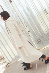 Tapado largo de paño color beige, con solapa amplia, mangas largas y cinturón ajustable para anudar en la cintura.