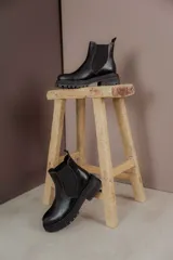 Bota Chelsea de cuero negro con elástico lateral y suela track.