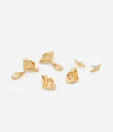 Kit de tres pares de caravanas de metal reciclado. Incluye un par pequeño en formato de pétalo, un par en formato de hoja y un par en formato de flor. Todas las caravanas son doradas, tienen cierre de tornillo y superficie irregular con relieve.