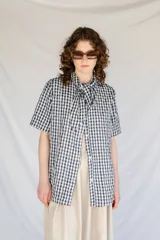 Camisa de algodón a cuadros gingham azul y blanco con estampado de broderie blanco, lazo en el cuello, manga corta y corte oversize.