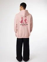 Hoodie de algodón orgánico color rosado con capucha y estampado en la espalda de dos personas cargando una tabla de surf junto al texto "GO OUT AND SLIDE" y caracteres en japonés.