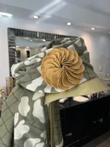 Broche con forma de flor color verde oliva, realizado artesanalmente en Italia con pétalos de cuero superpuestos. Se aplica con imán.