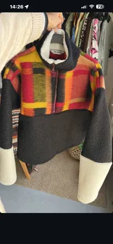 Buzo The Mood de corderito y tejido de lana, con diseño combinado de cuadros multicolores en la parte superior, negro en la parte inferior y mangas, y puños blancos. Cuenta con cuello alto y cierre frontal parcial.