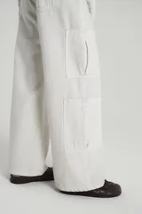 Pantalón jean color crudo, corte cargo, con botamanga ancha y tiro caído. Tiene bolsillos cargo en piernas, lavado stone wash con localizado y desgastes en costuras.