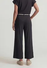 Pantalón acanalado de color negro, de corte recto y holgado, con cintura elastizada y cordón decorativo en tono crudo con cuentas de madera en los extremos.