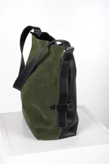 Bolso tipo bucket de gamuza color violeta con correa ajustable de cuero negro y detalles de costuras pespunteadas a la vista.