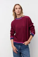 Pullover oversize de punto acanalado en color bordó, con cuello redondo y detalles de franjas en contraste en color azul y fucsia en el cuello, puños y ruedo.