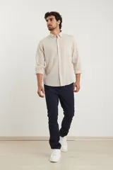 Camisa de manga larga confeccionada en una mezcla de algodón y lino, con cuello abotonado, cierre frontal de botones y un bolsillo en el pecho.