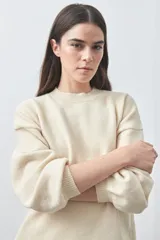 Sweater de tejido liviano con silueta relajada, hombros caídos y mangas largas con puños ajustados. Presenta cuello redondo y lazos ajustables en el bajo.