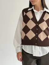 Chaleco tejido de punto con diseño de rombos en tonos marrón y beige, con escote en V y cierre frontal de botones.