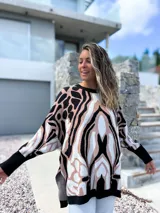 Sweater de punto con diseño oversize y estampado abstracto en tonos negro, beige y blanco. Presenta cuello redondo, mangas largas con puños ajustados y un corte holgado que cae suavemente sobre la figura.