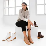 Botas cortas de cuero vacuno color marrón, con diseño de caña baja y cierre metálico en ambos laterales. Presentan un taco cuadrado de madera y suela de goma.