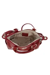 Cartera de mano color bordó con doble asa corta, correa larga ajustable y extraíble, y detalle de tachas metálicas verticales en el frente. Incluye un aplique metálico decorativo en forma de labios con strass en la parte superior central.