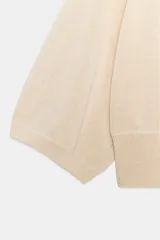 Jersey de punto color terracota, con cuello redondo y mangas amplias tipo murciélago.