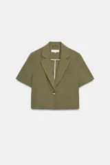 Blazer corto color verde oliva, de cuello solapa y manga corta. Tiene un bolsillo de vivo en el pecho y cierre frontal con un botón.