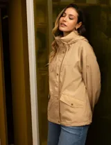 Campera color beige de poliéster, marca Michael Kors. Tiene cierre central oculto con botones a presión, bolsillos delanteros, capucha escondida en el cuello y avíos metálicos dorados con logo.