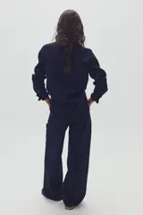 Camisa de denim azul marino con cuello clásico, mangas largas con puños abotonados y cierre frontal con botones.