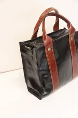 Cartera negra de cuero con doble correa marrón.