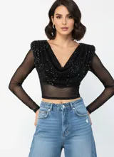Blusa de manga larga confeccionada en tela mesh semitransparente, con escote drapeado y detalles de pedrería brillante en el frente. Presenta un corte crop y diseño ajustado.