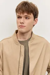 Campera bomber de gabardina color tostado, con cierre frontal y bolsillos laterales, puños y cintura elastizados de rib.