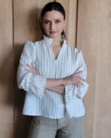 Blusa de algodón con cuello mao y volados, mangas largas con puños elásticos y corte holgado.