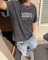 Remera de algodón con efecto lavado stone wash, de corte oversize y manga corta. Presenta un diseño gráfico estampado en la espalda con tipografía artística y texto alusivo a la cultura de barrio.