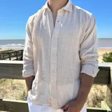 Camisa de lino de corte boxy, con cuello clásico, cierre frontal de botones y mangas largas con puños simples.