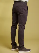 Pantalon tipo chino de corte ajustado, color gris oscuro, con cierre de boton y cremallera, y bolsillos laterales.