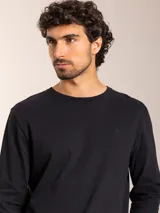 Remera blanca de manga larga con cuello redondo y logo bordado de un pájaro en el pecho.