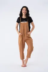 Enterito de lino color camel con tirantes ajustables que se anudan en los hombros y bolsillos laterales.