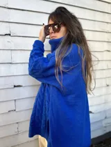 Sweater azul eléctrico de tejido de punto trenzado, cuello alto y corte oversize con aberturas laterales.