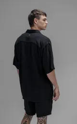 Camisa de manga corta con cuello solapa, confeccionada en lino. Presenta un corte oversize y cierre frontal con botones.