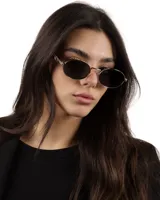 Lentes de sol ovalados con marco dorado y lentes oscuros.