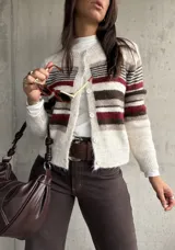 Cardigan de punto con diseño a rayas horizontales en tonos crema, marrón y bordó. Presenta cuello redondo, cierre frontal con botones y mangas largas.