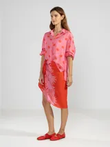 Camisa de manga larga color rosa con rayas verticales rojas y estampado de flores rojas. Con cuello camisero, puños elastizados y lazos regulables en los costados del ruedo.