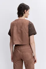 Chaleco de efecto piel color marrón con bordados decorativos de estilo étnico en el frente y cierre frontal con botones.