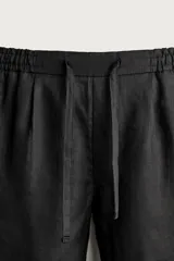 Bermuda de lino negro de corte relaxed fit, con cintura elástica ajustable mediante cordón y bolsillos frontales.