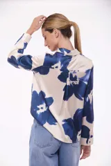Camisa de manga larga con estampado de flores azules sobre fondo color crema, con cuello clásico y cierre frontal con botones.