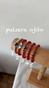 Pulsera elástica decorada con cuentas de cristal y dije de ojo turco, combinada con pequeños detalles metálicos.