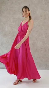 Vestido solera largo de seda color fucsia, con escote en V pronunciado en el frente y la espalda, y cintura elastizada.